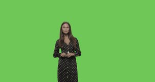 Close-up of smiling young woman in beautiful dress making sign heart shape by hand posing at green screen studio background. background, Chroma Key 4k video footage slow motion 60 fps