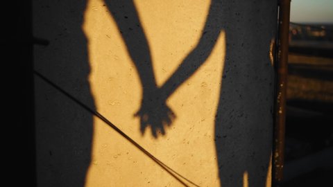 Shadows of lovers against the wall at sunset. Lovers hold hands. Stunningly beautiful silhouettes