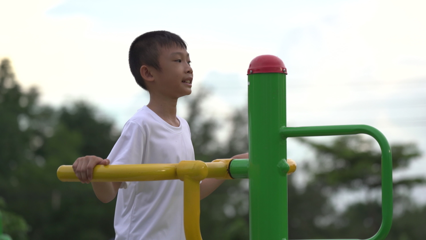 Kids playing and exercing on public outdoor gym park, boy children holding equipment and smile to enjoy play and exercise for good health for outside reaction on blurred background, Asian kids child