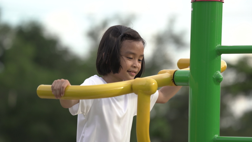 Kids playing and exercing on public outdoor gym park, girl children holding equipment and smile to enjoy play and exercise for good health for outside reaction on blurred background, Asian kids child