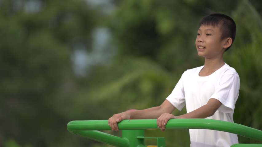 Kids playing and exercing on public outdoor gym park, boy children holding equipment and smile to enjoy play and exercise for good health for outside reaction on blurred background, Asian kids child