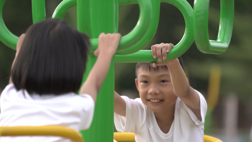 Kids playing and exercing on public outdoor gym park, boy girl children holding equipment and smile enjoy play and exercise for good health for outside reaction on blurred background, Asian kids child