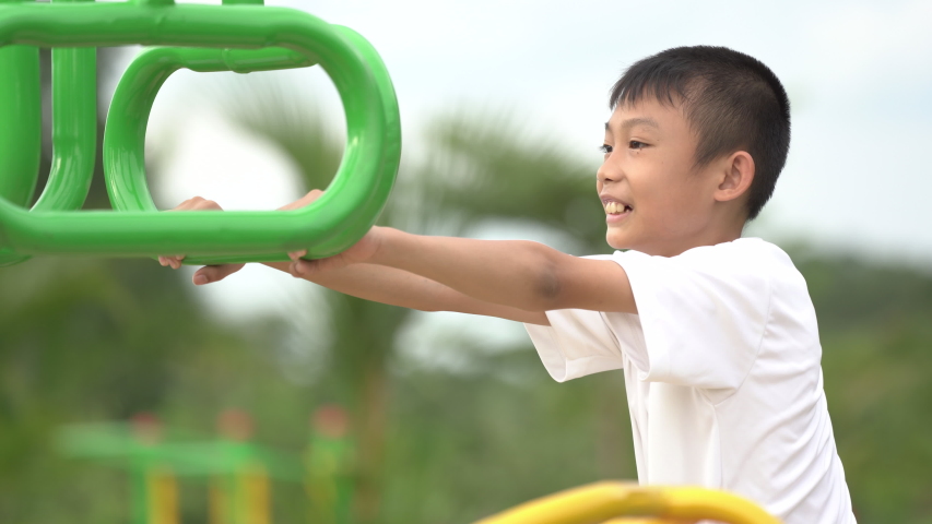 Kids playing and exercing on public outdoor gym park, boy children holding equipment and smile to enjoy play and exercise for good health for outside reaction on blurred background, Asian kids child