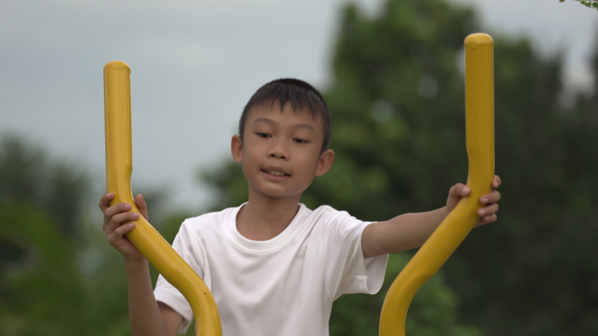 Kids playing and exercing on public outdoor gym park, boy children holding equipment and smile to enjoy play and exercise for good health for outside reaction on blurred background, Asian kids child