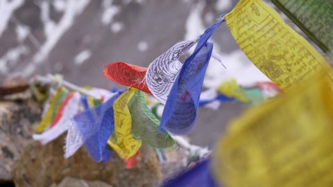 Close up slow motion shot of Buddhist praying flags waving with the wind in the mountainous region next to a monastery. 