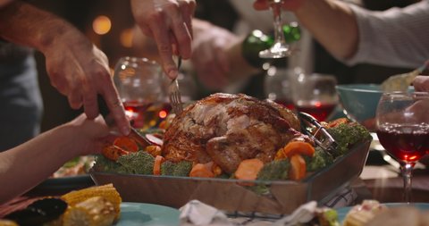Close up shot of people eating delicious roasted turkey during thanksgiving or christmas dinner party, filling up plates and glasses - food and drink, celebration 4k footage