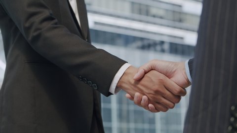Close up. Hand of two Asian business people gathered to shaking hands agree to a deal or say hello On the background of building in city