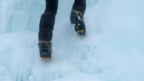 Crampons close-up on his feet ice climber on a frozen waterfall. Shards of ice.