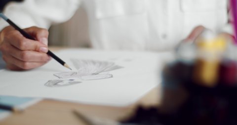 Close up of female designer using pencil and sheet of paper for fashion sketches. Mature woman in white blouse creating design of new clothing collection.