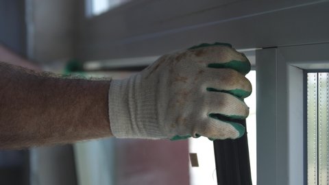 Worker put window sash into new installed frame. Close up of hand