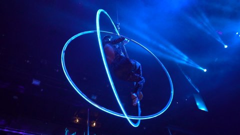 Woman in a cat costume whirls in an aerial acrobatic hoop, night club performance