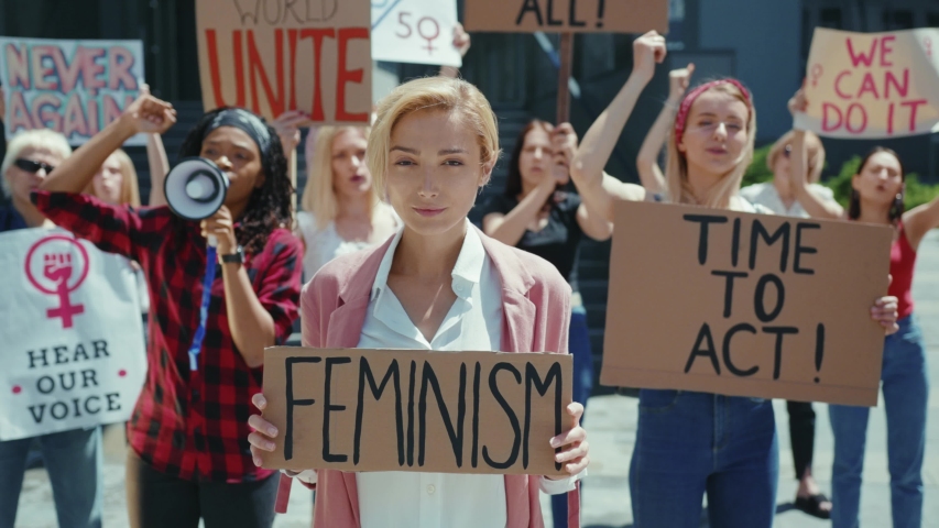 Smile attractive woman with feminism poster participating in protest. Group of friendly diverse young women protesting for freedom and equal rights. | Shutterstock HD Video #1056263960