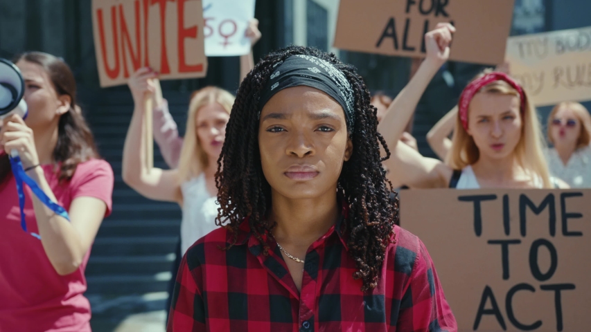 Feminist Demonstration. Vigorous chanting crowd of active girls protesting for women rights. Attractive black girl leader look at camera. Girl power. March movement. | Shutterstock HD Video #1056263978