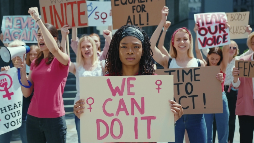Feminism. Girl Power. We Can Do It. African american female activist with poster taking part in mass feminist empowerment action demonstration. Protest. | Shutterstock HD Video #1056263981