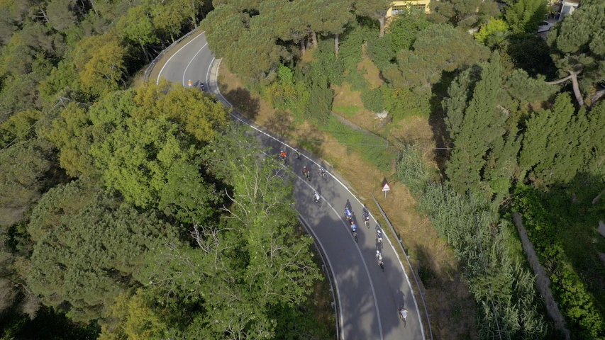 Aerial Drone follow-up view of a group of cyclists going down a serpentine road in the mountain woods Royalty-Free Stock Footage #1056264902