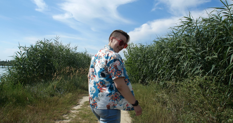 Tracking shot. Camera following a female tomboy. Pretty stylish girl with short creative hairstyle running away from camera having fun and laughing . 4k slow motion 50 fps