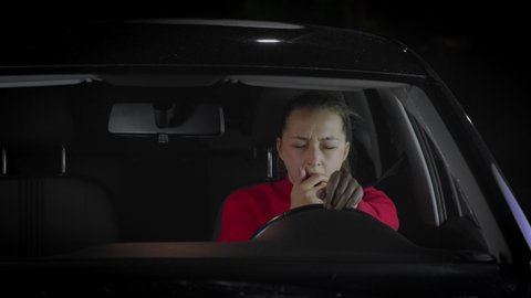 Caucasian woman yawns and falls asleep while driving a car. Night trip, travel by personal car. Unsafe driving. The driver sleeps at the wheel due to fatigue concept.