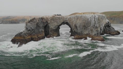 Aerial fly-through of a large arch in the Pacific Ocean near the Sonoma Coast in California.