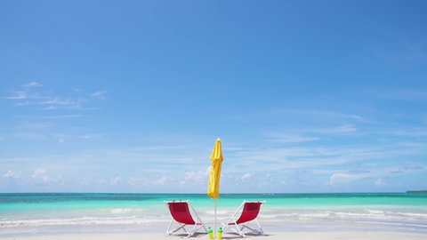 Vacations on Hawaii beach resort. Sea beach tranquility with sunny accessories deck chairs and sun umbrella on unaffected transparent white sandy beach. Amazing azure sea and blue sky beach seascape.