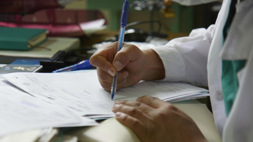 A close up of a Doctor's hand as he fills out some paperwork in his office in a Peruvian Hospital. Royalty-Free Stock Footage #1056284105