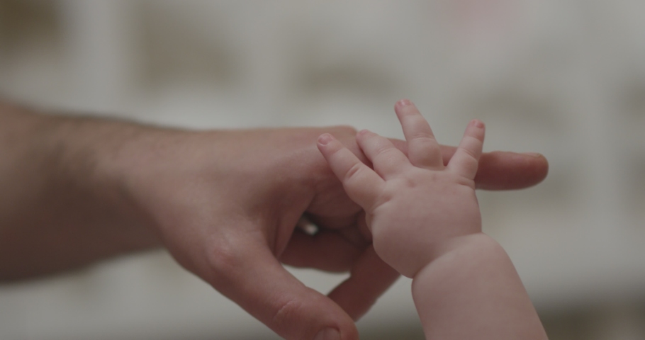 Close-up shot of baby's little cute hand reaching for father's loving finger . Baby holding parent's finger . Parent holding newborns hand in Slow Motion . Hand in hand. Father and his newborn baby .  | Shutterstock HD Video #1056285365