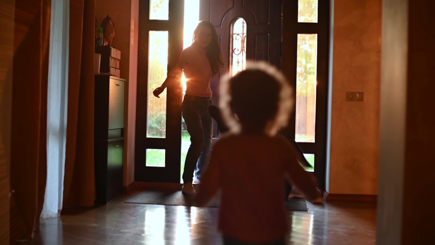A child meets mom from work. The girl joyfully runs to the front door, where her mother enters, Backlight, camera moves | Shutterstock HD Video #1056287180