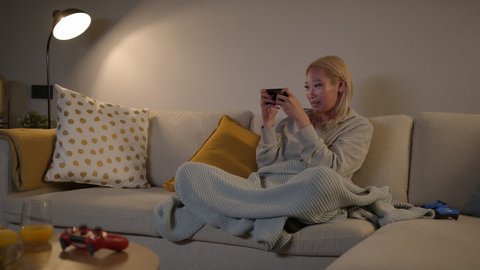 Slomo: Overjoyed Focused Pretty Southeast Asian Woman Playing Mobile Games On A Smartphone And Winning