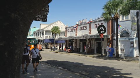 Key West, Florida - December 4, 2019: People walk along the historic architecture of bars, restaurants and shops on famous Duval Street in Key West Florida USA.
