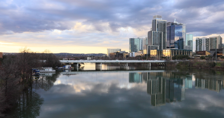Austin Texas river lake sunset pan across city skyline. Brilliant sunset colors. Lady Bird Lake. Skyline of the city along the shore.