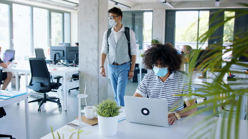 Young people with face masks back at work in office after lockdown, greeting. Royalty-Free Stock Footage #1056293702