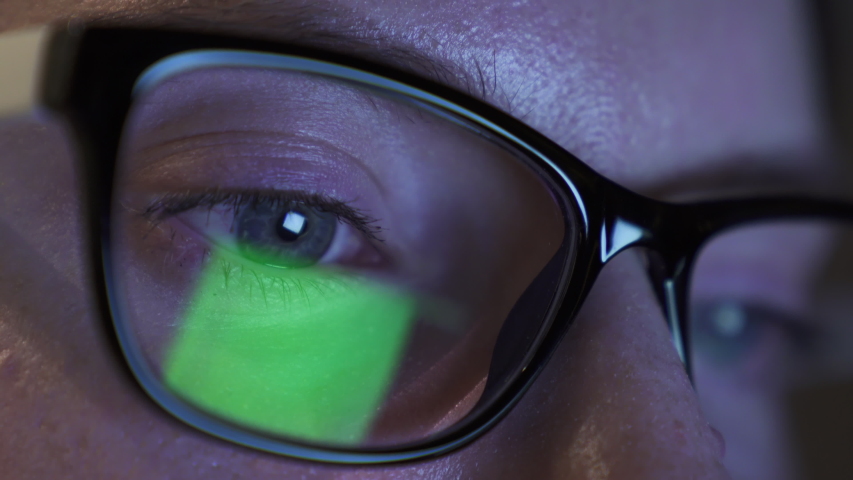 Detailed view on female eyes in glasses, watching on the screen and read something quick, nervous moving of pupils. Reflection of screen of laptop in eyes. Cold light of the screen on face. Night. 4K. | Shutterstock HD Video #1056294356