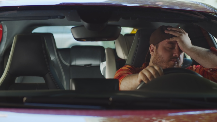Young stout man sitting in car very upset and stressed after hard failure and moving in traffic jam. Frustrated and exhausted fat guy feeling angry sitting his car Royalty-Free Stock Footage #1056297086