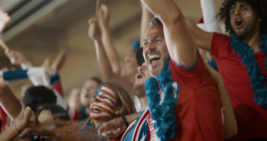 Excited fans celebrating in stands. American soccer supporters cheering over a goal in stadium.
