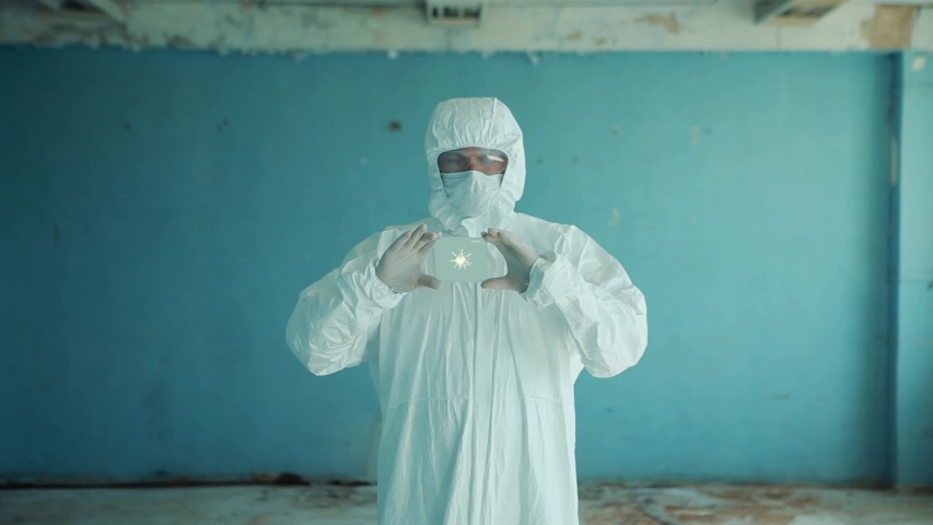 A man in a protective suit and glasses is a concept of futuristic medicine, a laboratory assistant is holding new technologies in his hands, a laboratory of the future.
