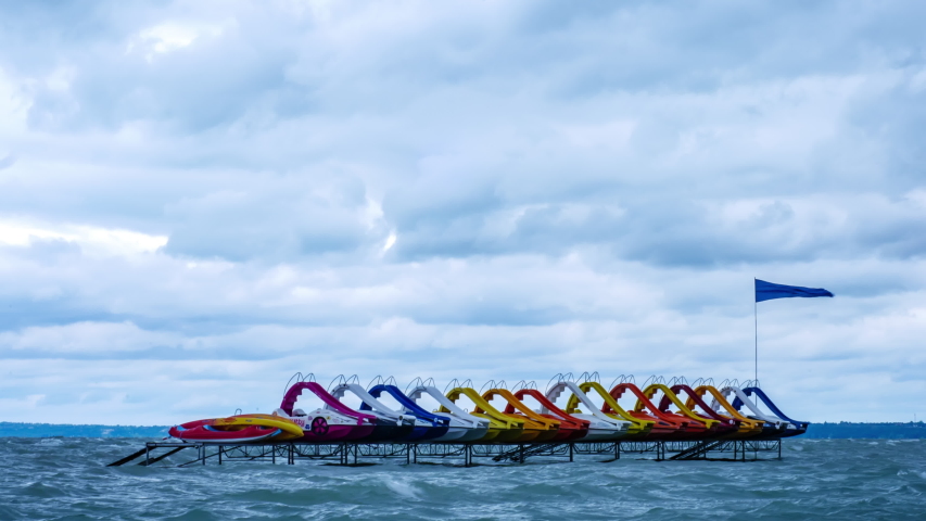 Time-lapse view on the water paddle bikes beach boats on the Balaton Lake on a stormy day.