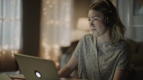 Girl using laptop and listening to music on headphones at night / Cedar Hills, Utah, United States