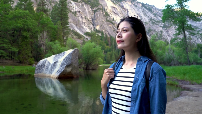 Yosemite National Park reflection in merced river of waterfalls and beautiful mountain landscape California USA. young beautiful asian happy girl backpacker standing by mirror lake outdoor relax.