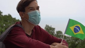 Vacation and travel during the coronavirus pandemic. Traveler with the flag of Brazil. Summer holidays. A young man in a medical mask is traveling. Covid-19 social distancing and protective measures - Powered by Shutterstock - Get 15% off with code: PIKWIZARD15