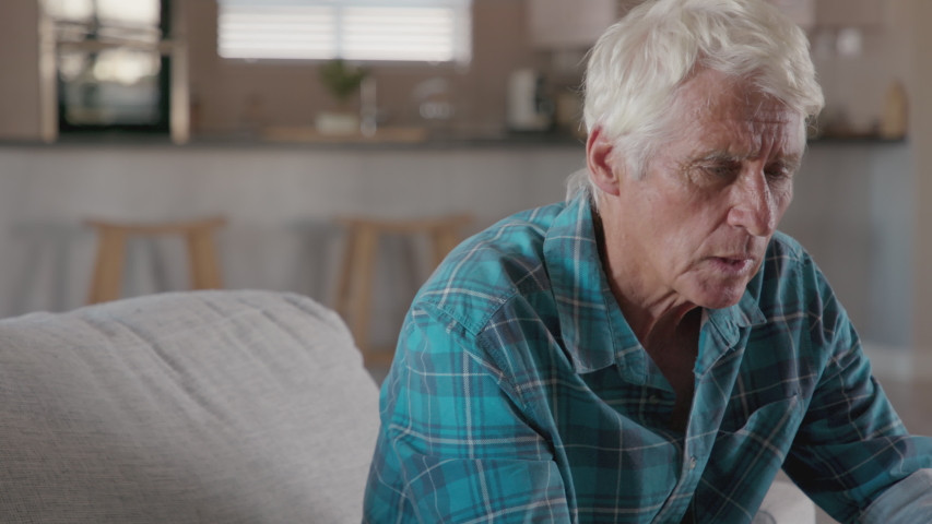 Senior man holding ears while suffering from pain. Side view of senior man with symptom of hearing loss, copy space. Mature tensed man sitting on couch with fingers near ear suffering pain. Royalty-Free Stock Footage #1056319703