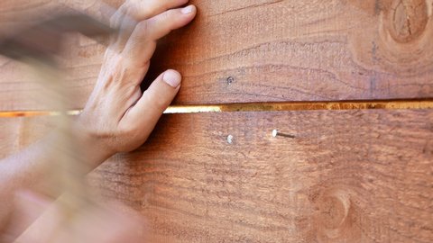 Close up of man's hands hammering a nail into a wooden wall