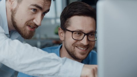 Cheerful caucasian office employee sharing great business news with boss team leader looking on computer screen in coworking space.