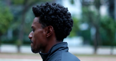 Pensive man walking in city, thoughtful black african american walks in urban sidewalk.
