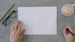 Top view shot of a man pretending to write with his pen on a stack of a4 sheets of paper placed on a marble table top surface with coffee, reading glasses and office utensils. - Powered by Shutterstock - Get 15% off with code: PIKWIZARD15