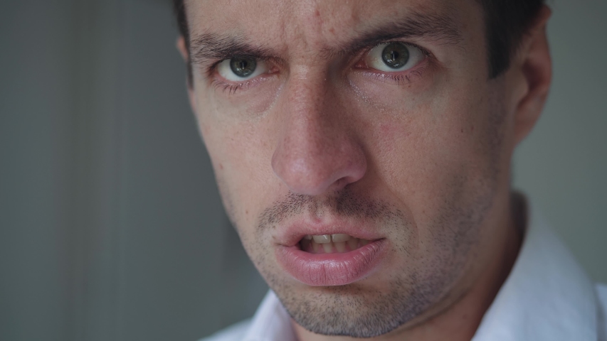 Man with angry facial expression is screaming out loud. Close-up mouth of angry man screaming. Threat of violence. Royalty-Free Stock Footage #1056325427