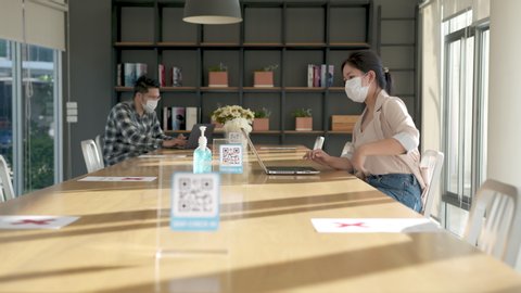 Asian employee wearing face mask in new normal office. Check in and cleaning hand before use co working space or flexible office. Lifestyle and work after corona virus (Covid-19).