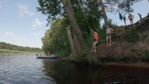 Jumping into the water with a life jacket. Children bungee jumping into the river. Tver Oblast, Russia 07/2020