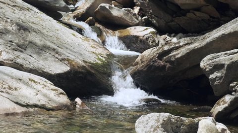 Picturesque view of fresh clean stream of river water cascading and meandering down rocks into natural shallow clear pool of water, static close up slow motion