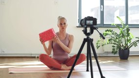 fitness, sport and video blogging concept - woman or blogger with camera on tripod and exercise block recording online yoga class in gym or studio - Powered by Shutterstock - Get 15% off with code: PIKWIZARD15