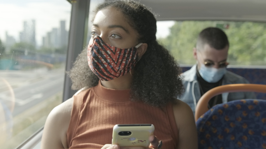 Young adult afro American woman sitting on the bus wearing face mask during coronavirus pandemic | Shutterstock HD Video #1056340475