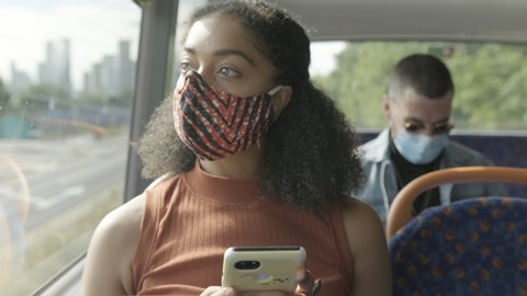 Young adult afro American woman sitting on the bus wearing face mask during coronavirus pandemic